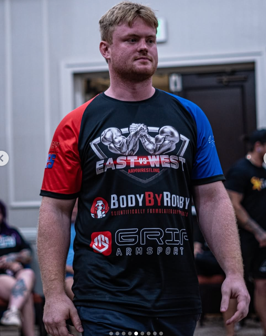 Person wearing a raglan sublimation t-shirt with various logos in an indoor setting